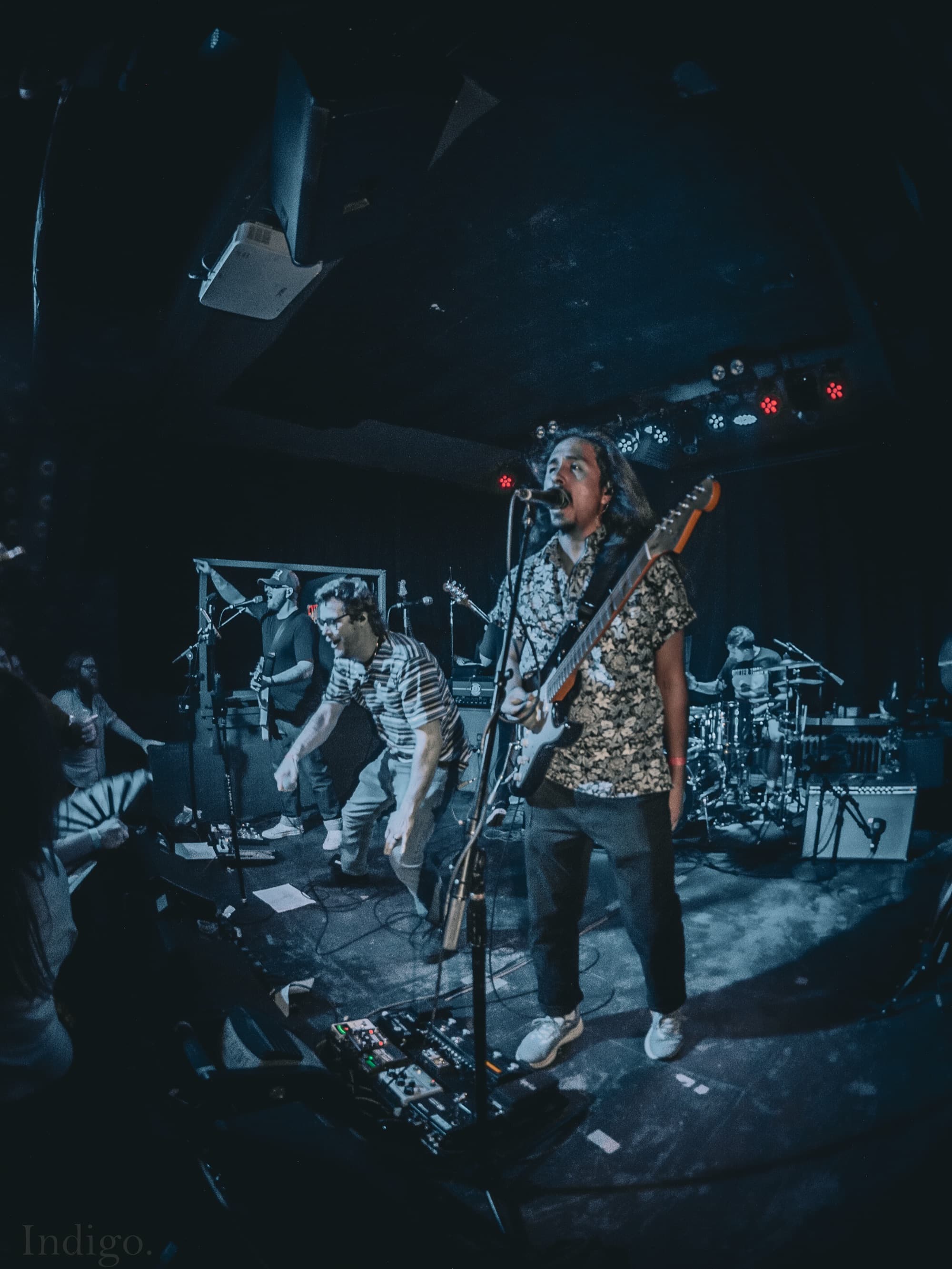 Guitarist singing into mic on dark stage